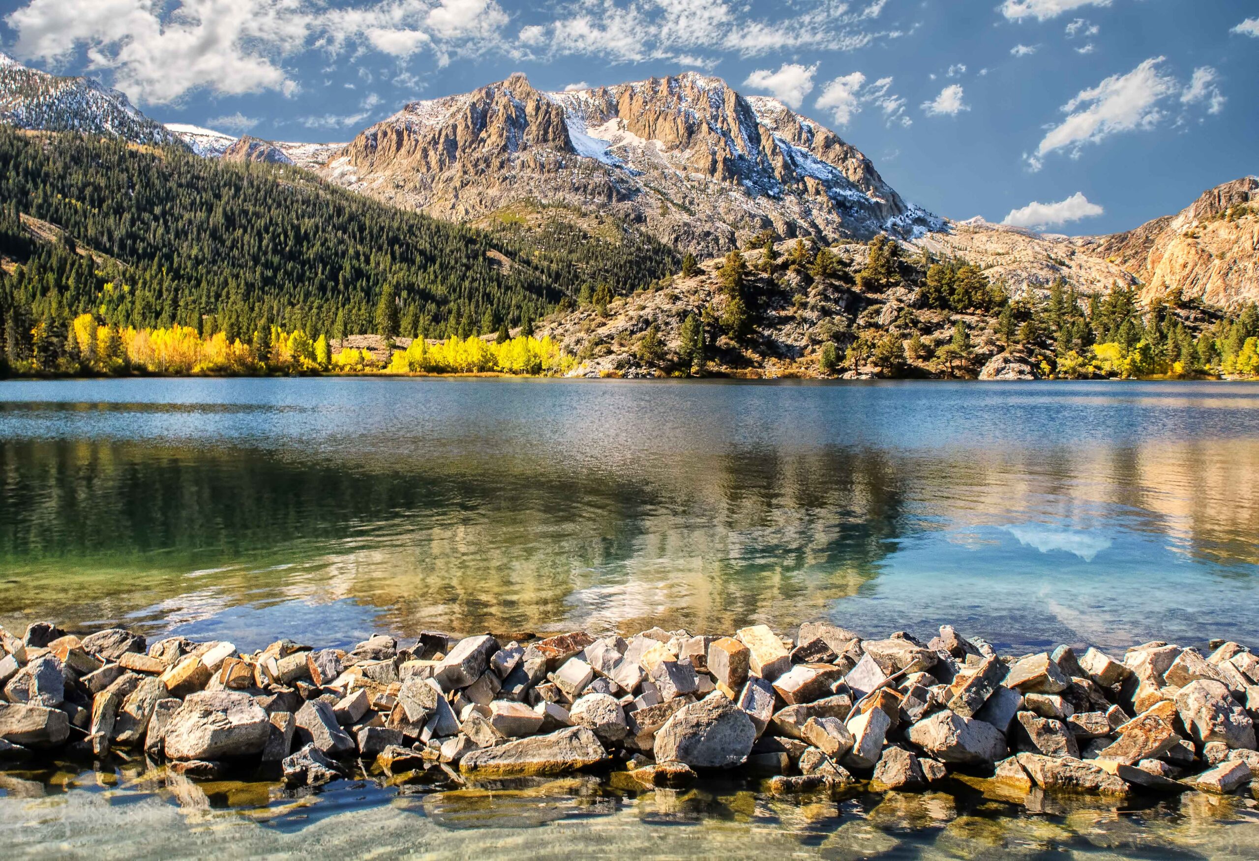 Alpine lake with rocky shore and mountain reflection